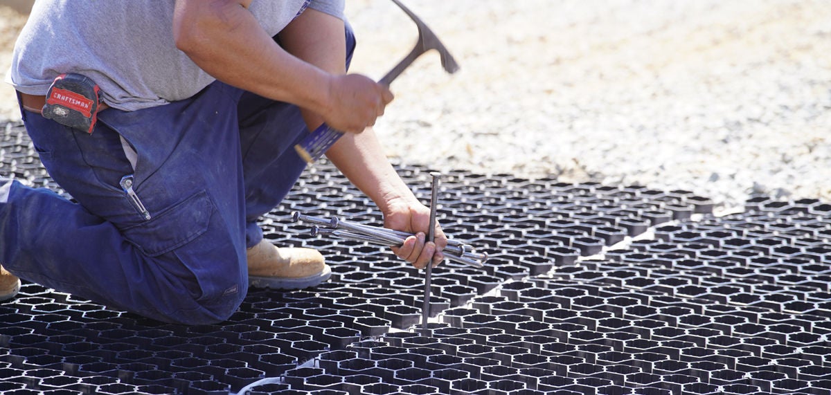 person installing pavers using a hammer at a job site