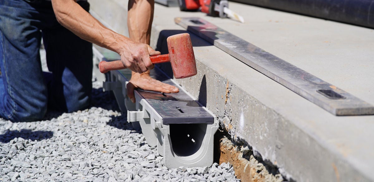 man with hammer installs duraslope trench drain