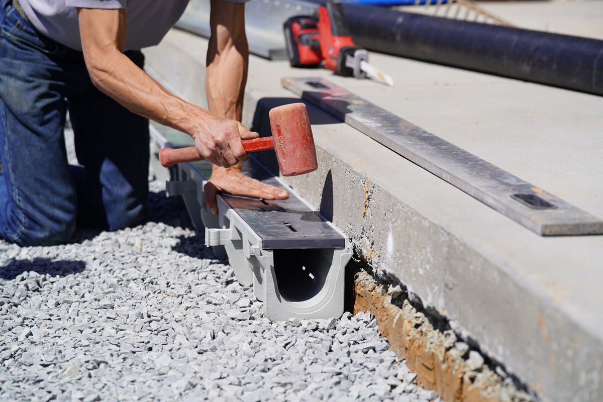 man with hammer installs duraslope trench drain